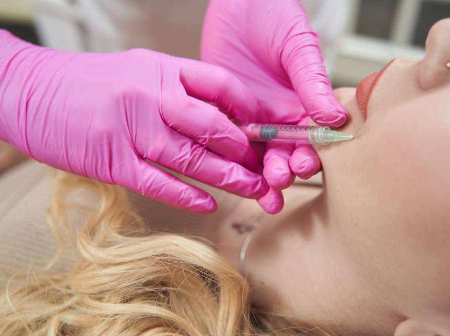 Elegant woman is getting injection of anti aging filler in cosmetology office