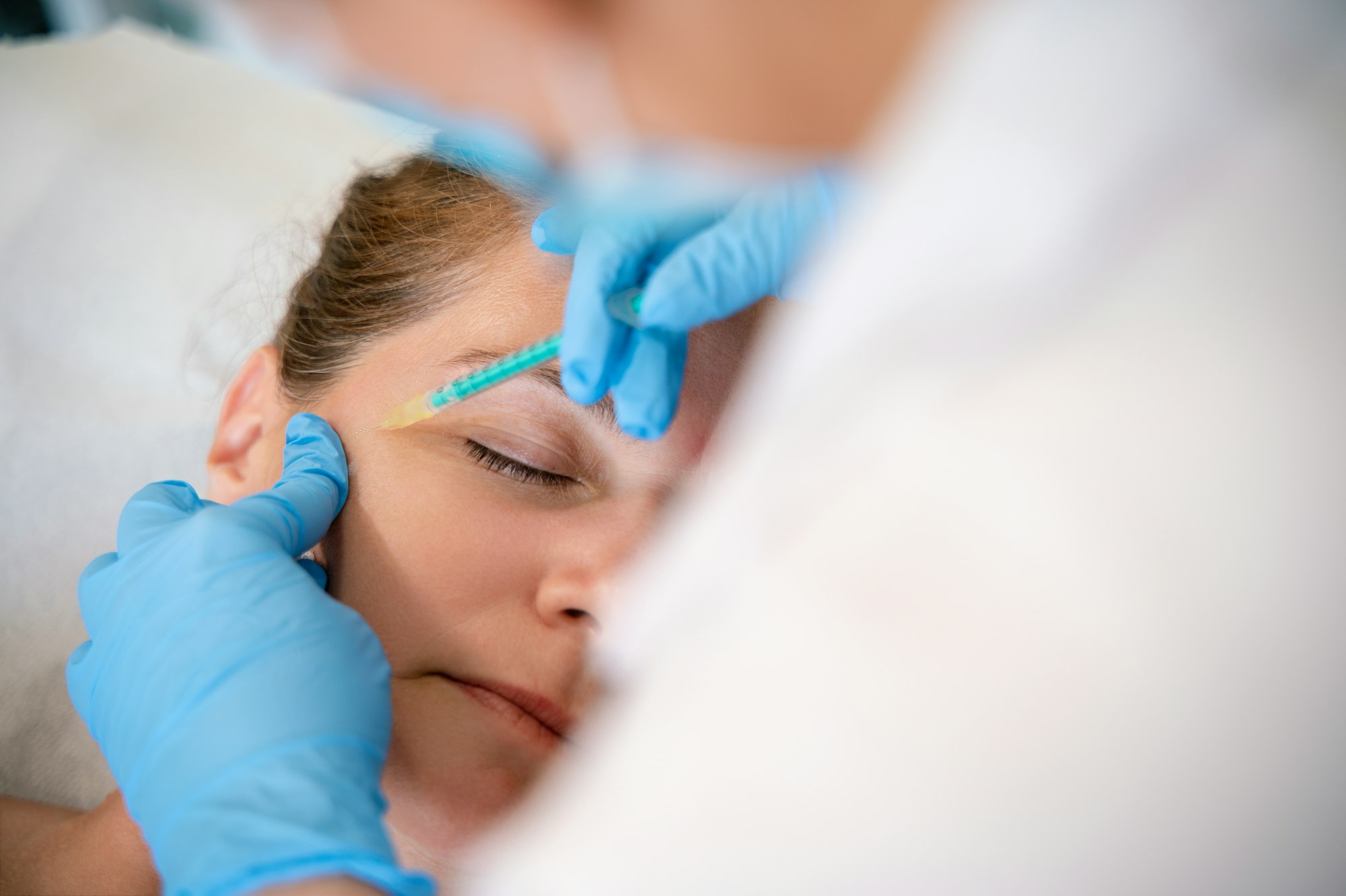 Physiotherapist giving facial injection to client in clinic